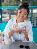 jeune femme souriante à la terrasse d'un bar avec un Mug Éclat Astral Vierge en céramique rose dans les mains