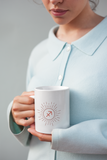 jeune femme pensive avec un Mug Constellation Sagittaire dans les mains